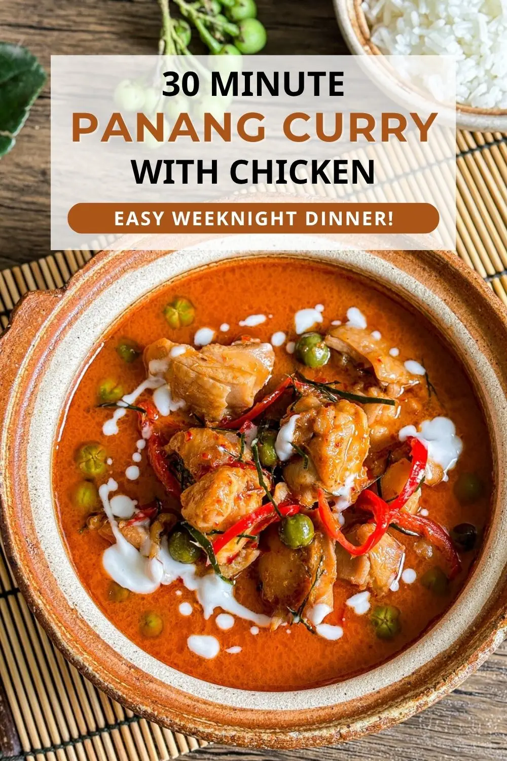 Top-view of panang curry chicken with coconut milk, red chilies, pea eggplants, and kaffir lime leaves.
