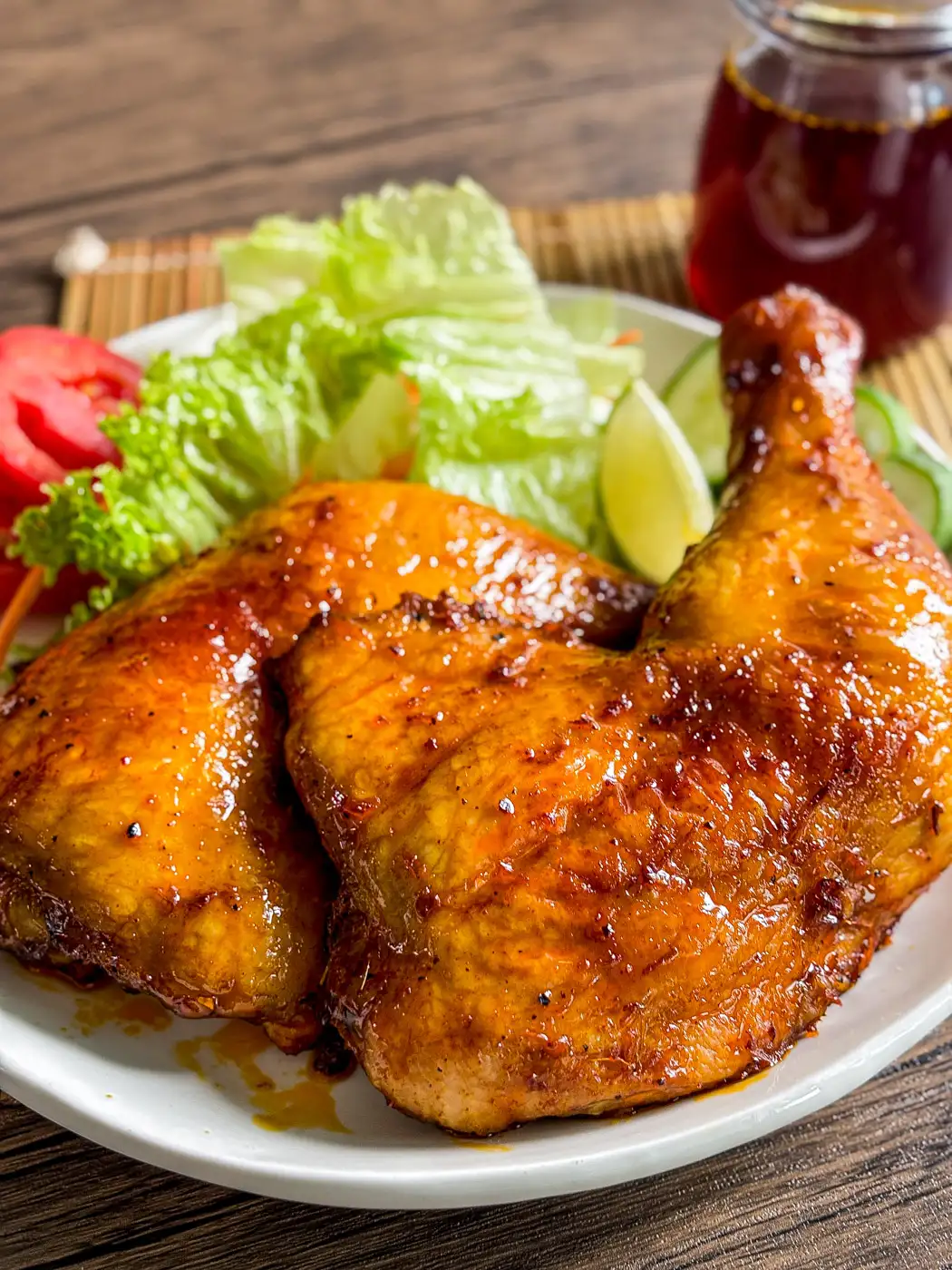 Close-up of juicy Bacolod-style chicken inasal with a golden glaze, served with a fresh salad on the side.