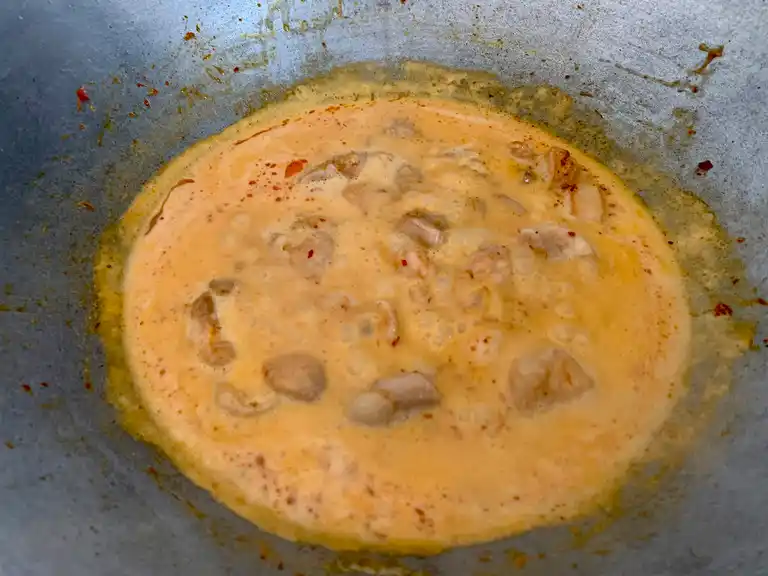 Chicken simmering in coconut milk with Thai red curry sauce.