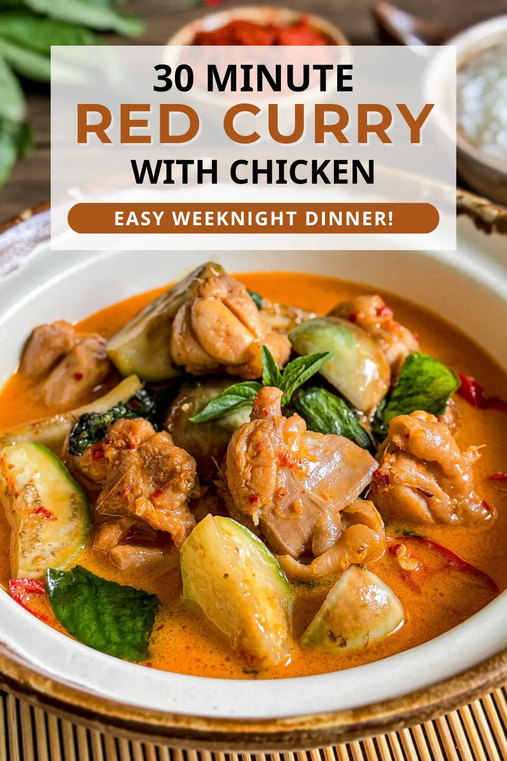 Close-up of Thai red curry chicken with Thai eggplants, chilies, and Thai basil in a traditional bowl.