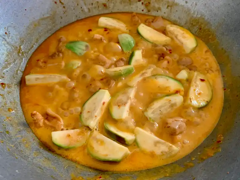 Fresh Thai eggplant simmering in red curry sauce with chicken.