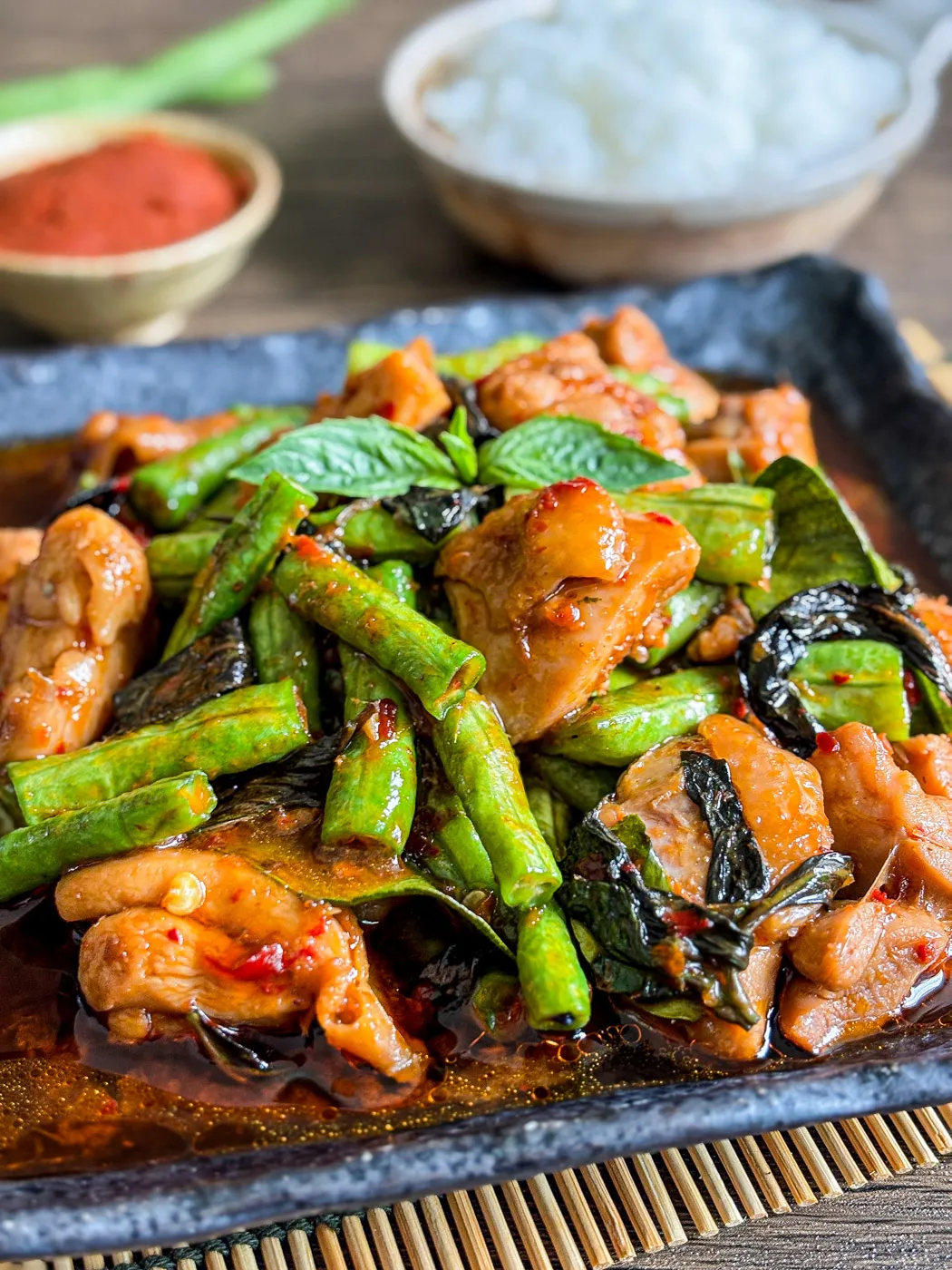 Close-up of Thai gai pad prik gaeng with stir-fried chicken in curry paste and vegetables on a dark plate.