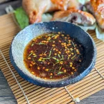 Thai grilled chicken sauce with red pepper flakes and herbs, served with juicy grilled chicken legs on lettuce.