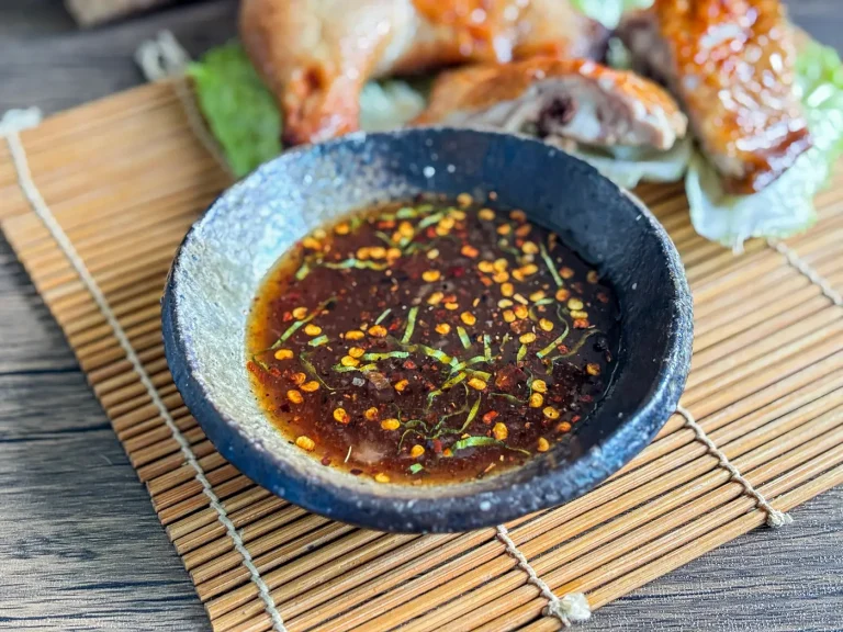 Thai grilled chicken sauce with red pepper flakes and herbs, served with juicy grilled chicken legs on lettuce.