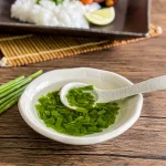 Vietnamese mo hanh scallion oil with chopped green onions in a small white dish, ready to spoon over rice or noodles.