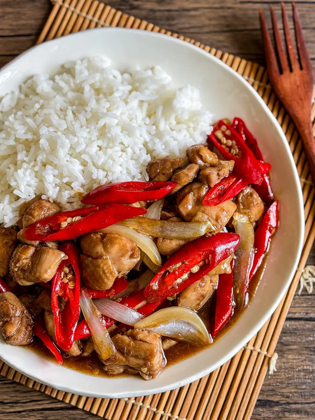 pad prik chicken close-up with large red chilies, onion, and rich sauce, served alongside white rice.