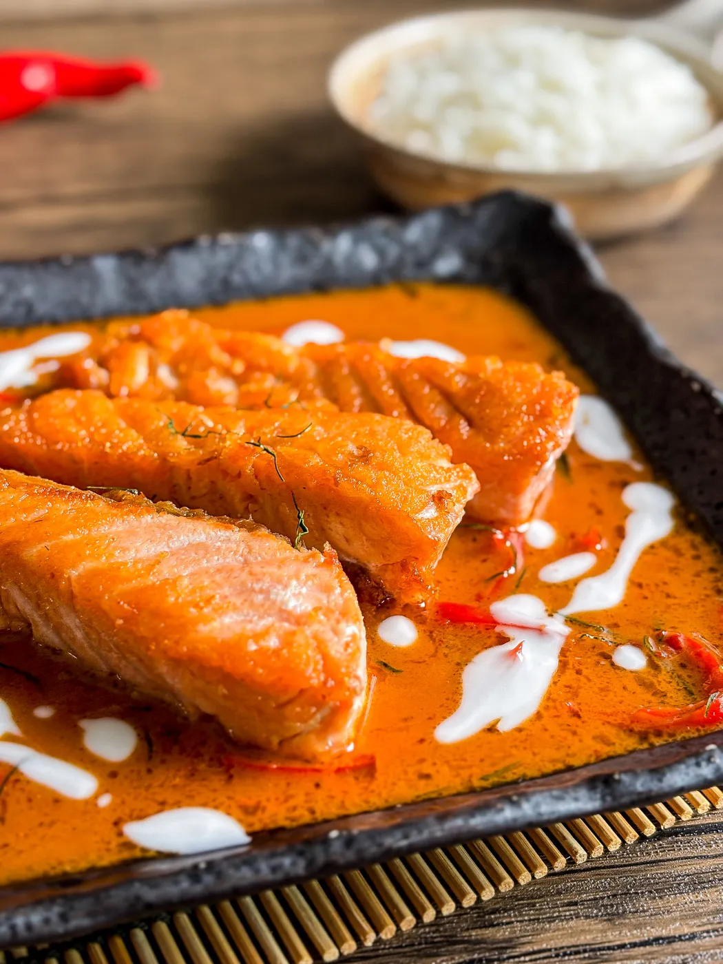 Close-up of Thai choo chee salmon curry with creamy red curry sauce, coconut milk, and red chilies, served with steamed rice.