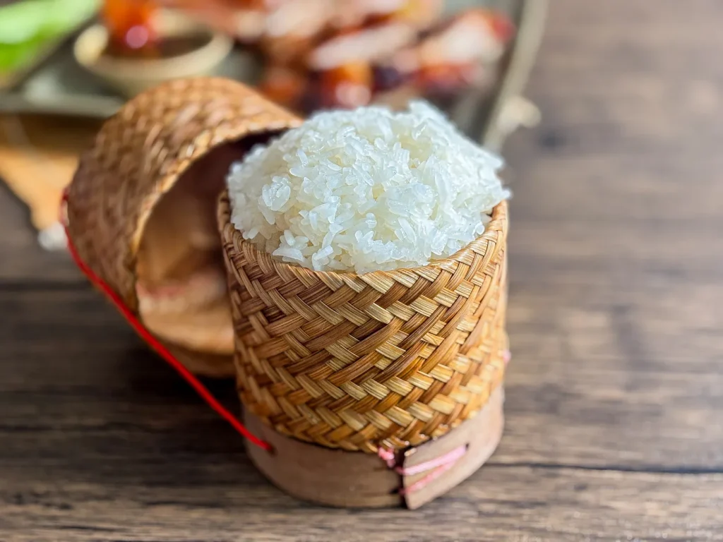Thai sticky rice served in a traditional woven bamboo basket on a wooden table.