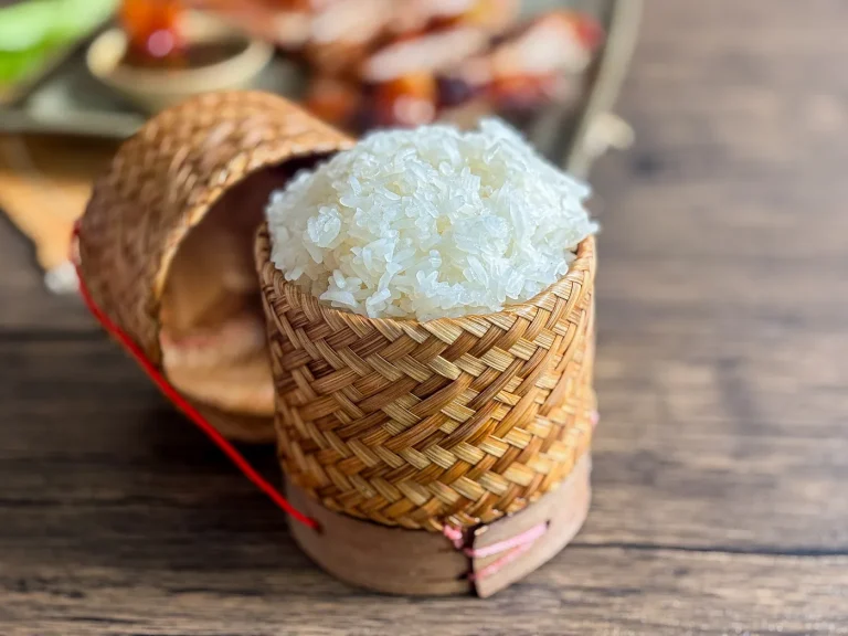 Thai sticky rice served in a traditional woven bamboo basket on a wooden table.