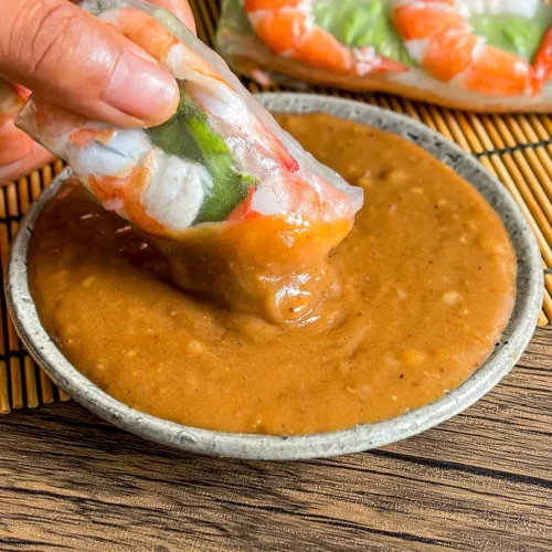 Vietnamese peanut hoisin sauce served with shrimp spring rolls on a bamboo mat.