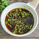 Stir-fry pan filled with Thai basil sauce made with fresh garlic, chilies, and holy basil leaves.