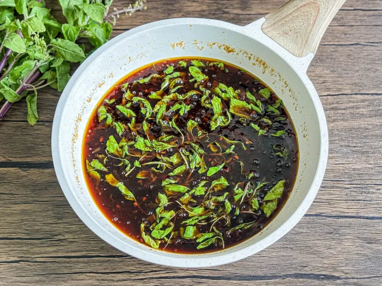 Stir-fry pan filled with Thai basil sauce made with fresh garlic, chilies, and holy basil leaves.