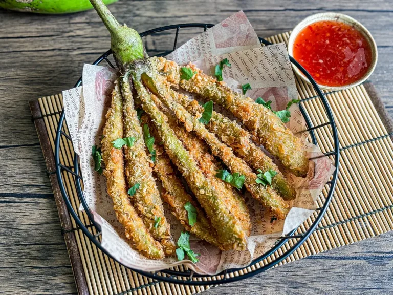 deep-fried eggplant served with sweet chili dipping sauce on the side, presented on a bamboo mat.
