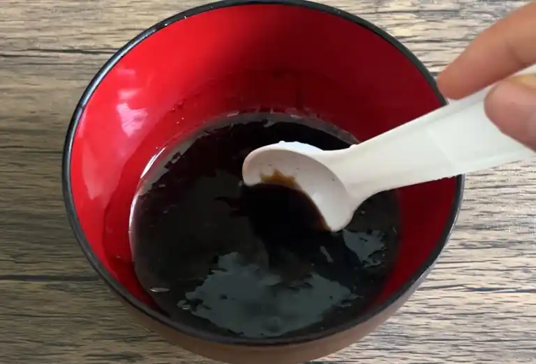 Stir-fry sauce mixture with soy sauce and seasonings in a red bowl.