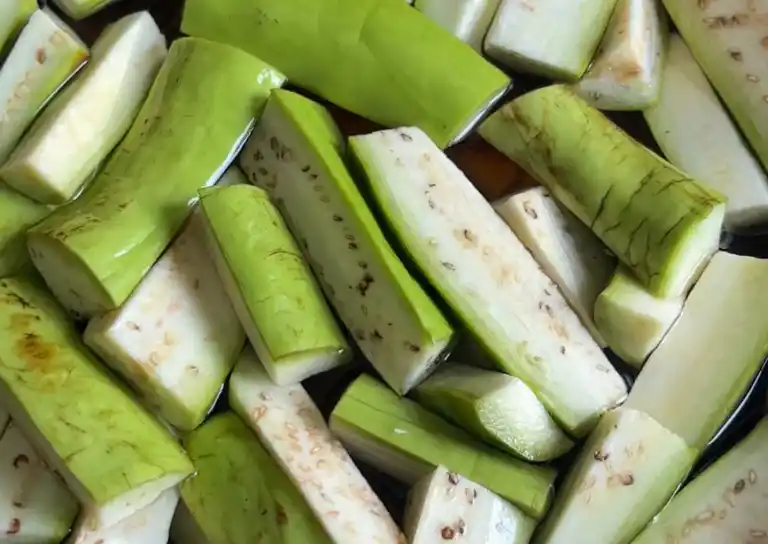 Sliced eggplant soaked in a bowl of salted water.