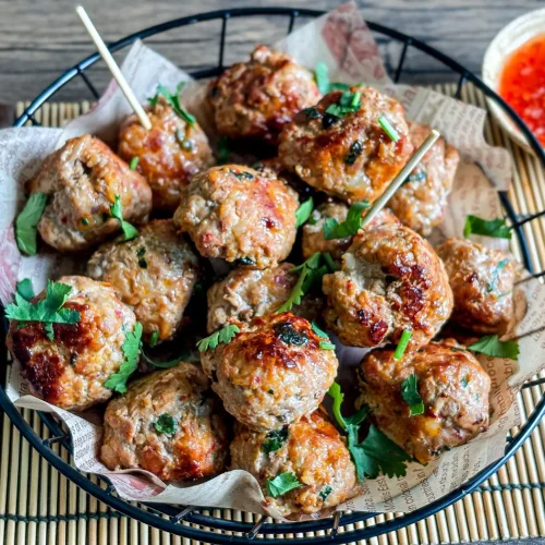 Thai meatballs garnished with cilantro, served with a side of sweet chili sauce.