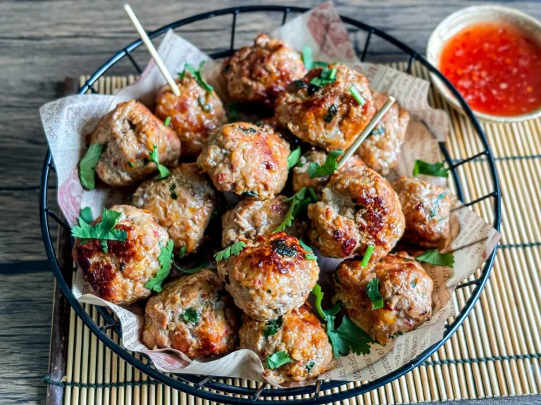 Thai meatballs garnished with cilantro, served with a side of sweet chili sauce.