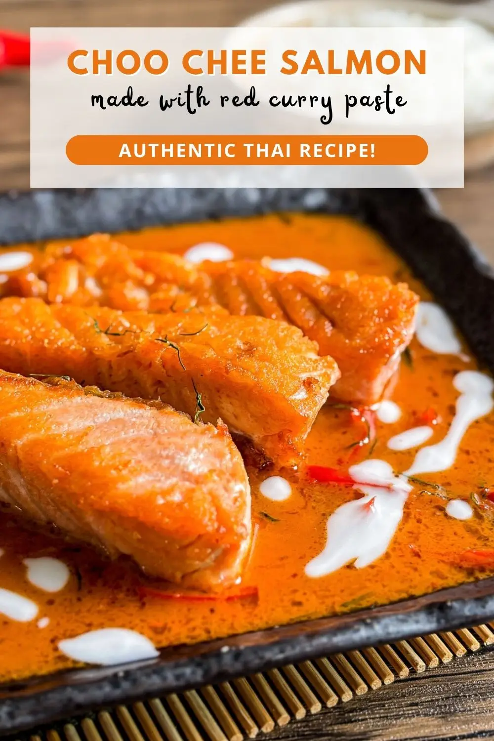 Choo chee salmon curry served in a black dish with coconut milk drizzle and kaffir lime leaf garnish.