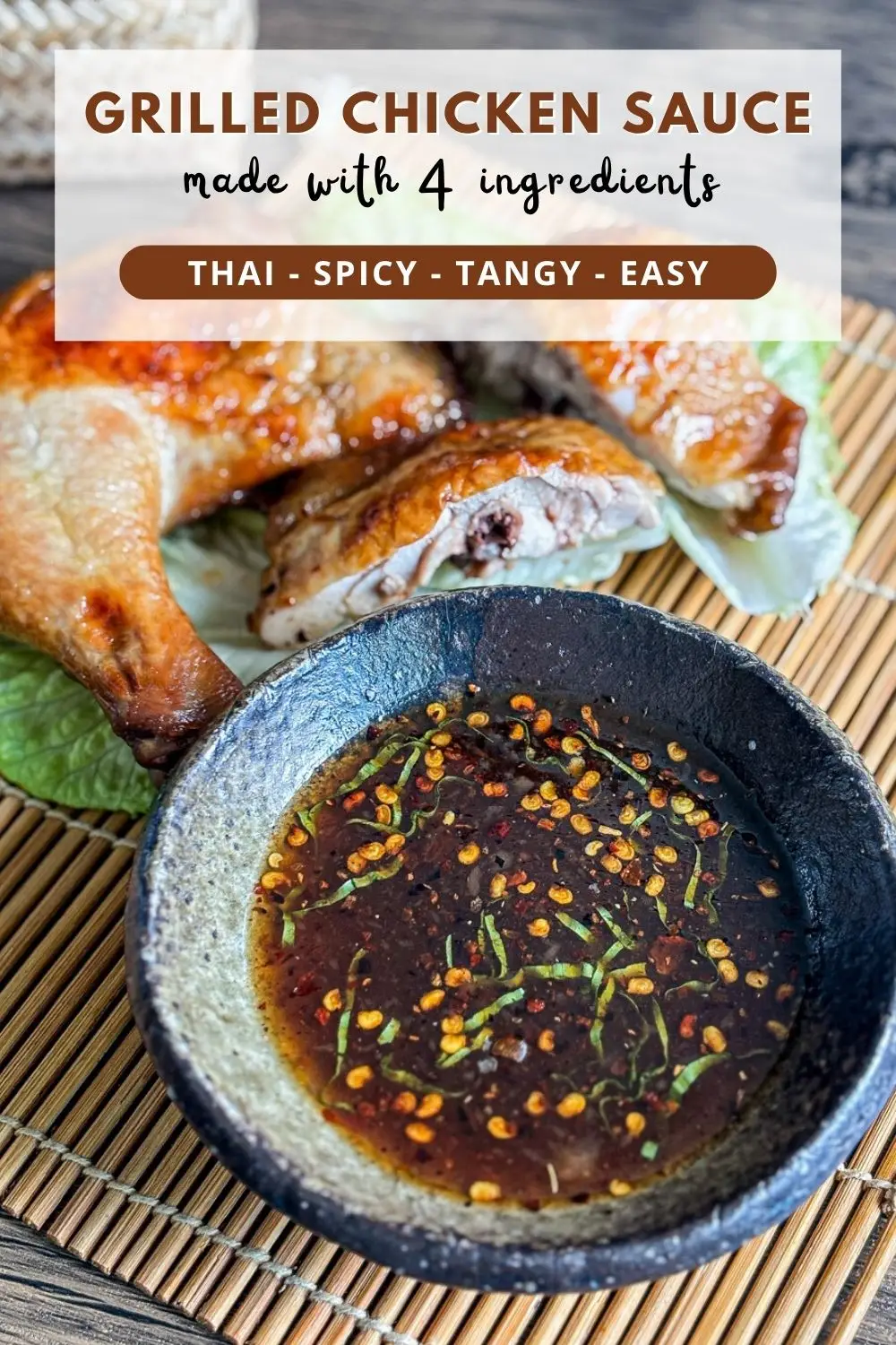 Thai grilled chicken dipping sauce with chili flakes and herbs served in a small black bowl, with grilled chicken pieces on the side.