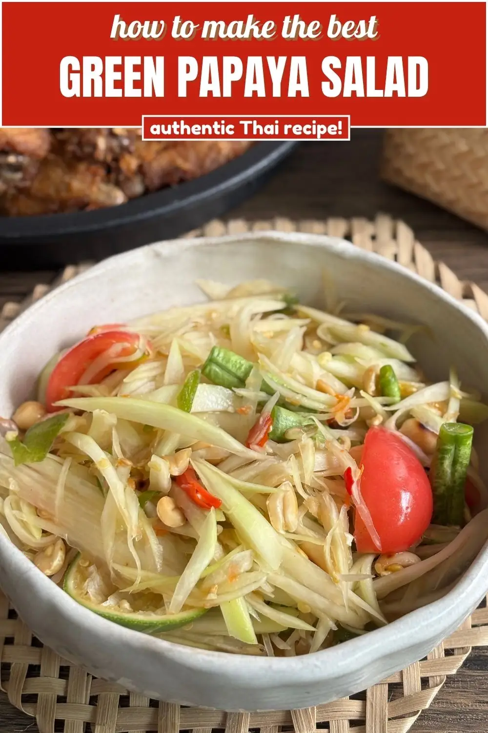 Authentic Thai green papaya salad with shredded papaya, tomatoes, long beans, chilies, and peanuts in a white bowl.