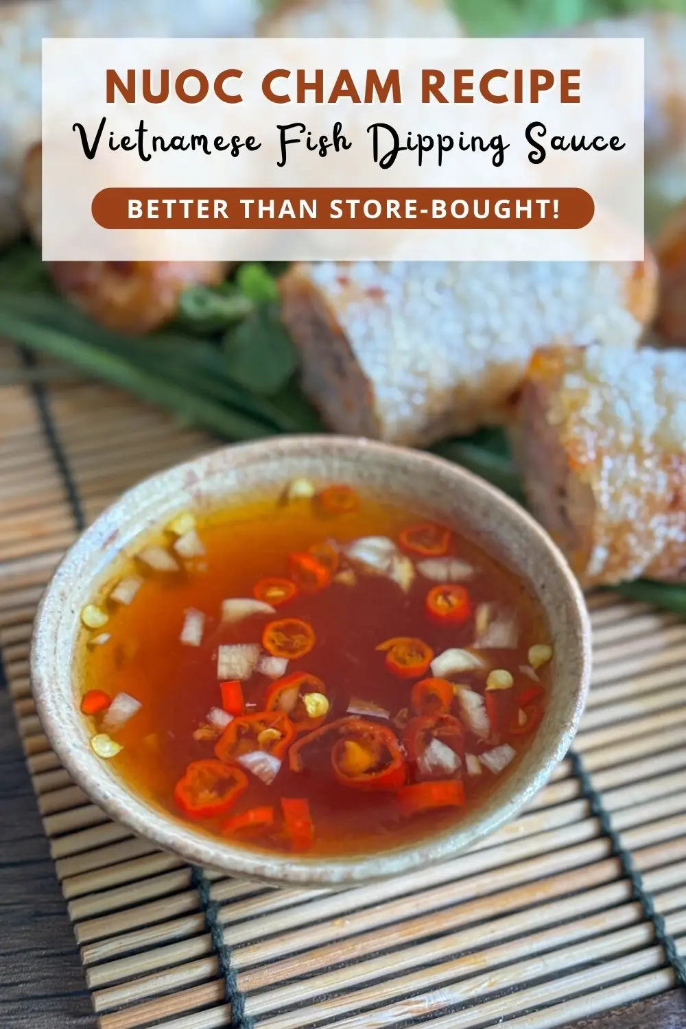 Vietnamese nuoc cham fish sauce dipping sauce with chopped chilies and garlic in a ceramic bowl, served with crispy spring rolls.