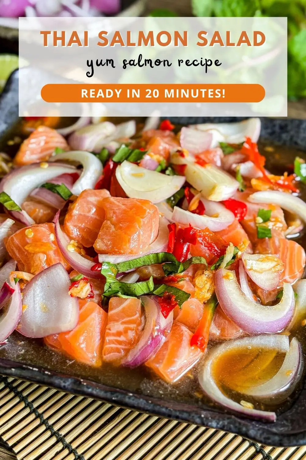 Thai salmon salad with raw salmon chunks, red onion, chilies, and herbs in a spicy lime dressing served on a black plate.