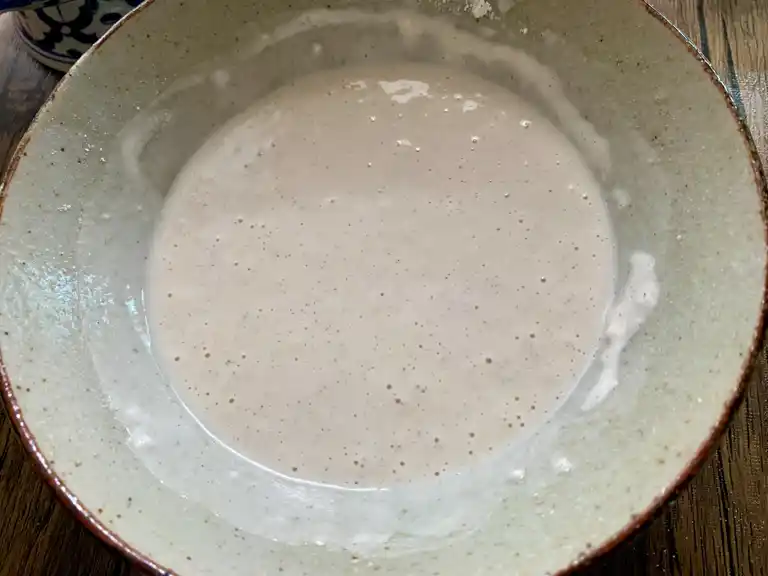 Mixed tempura flour and ice-cold water forming smooth batter.