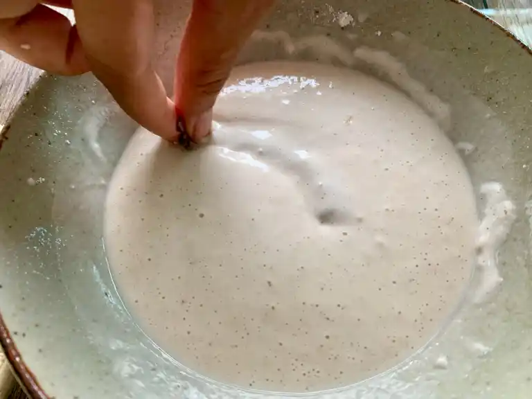 Shrimp being dipped into cold flour batter.