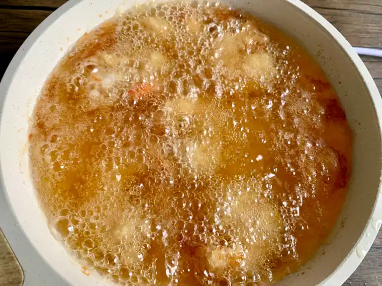 Panko shrimp frying in hot oil until golden and crispy.