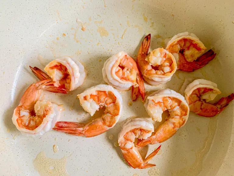 Shrimp frying in a non-stick pan until cooked through.
