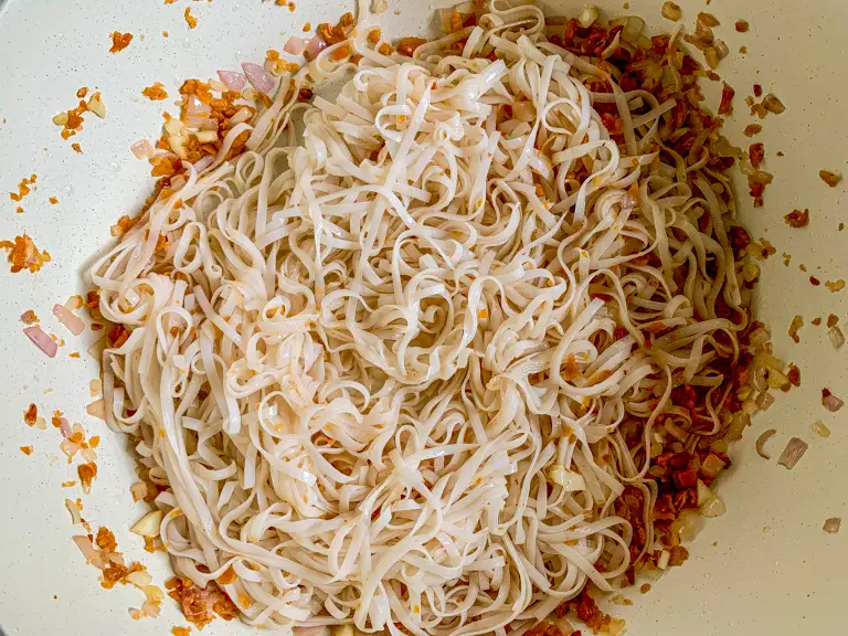 Noodles and aromatics gently tossed together in the wok.