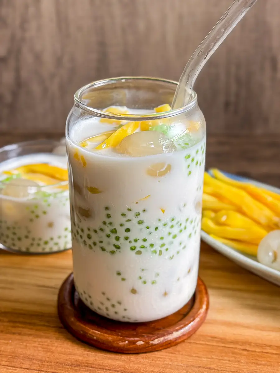 Thai nam wan drink served in a tall glass and a short glass, filled with coconut milk, green tapioca pearls, and sliced jackfruit.