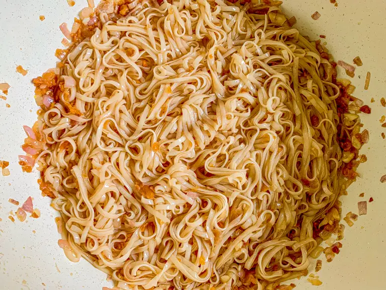 Rice noodles evenly coated with homemade pad Thai sauce.