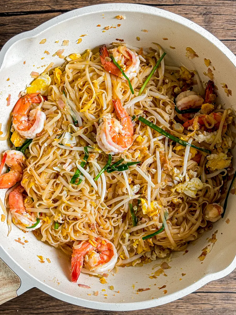 Wok with freshly cooked pad Thai shrimp noodles, stir-fried with egg, bean sprouts, and garlic chives.