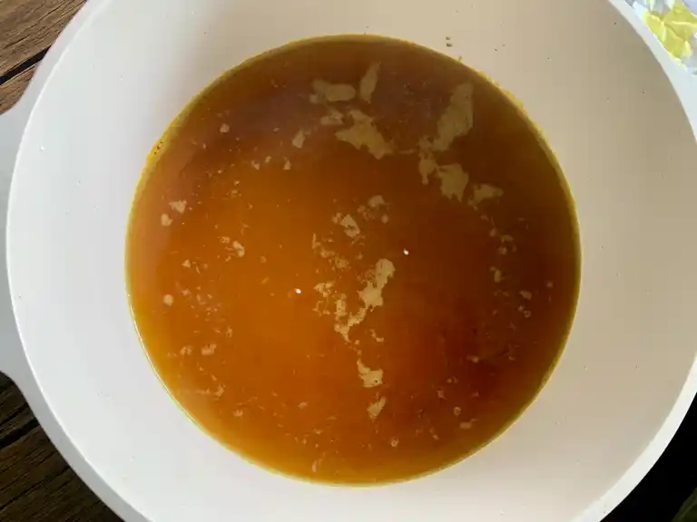 Pot of golden broth with soy sauce and turmeric added.