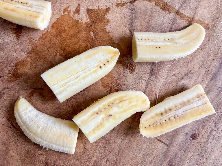 Sliced saba bananas on a wooden board.