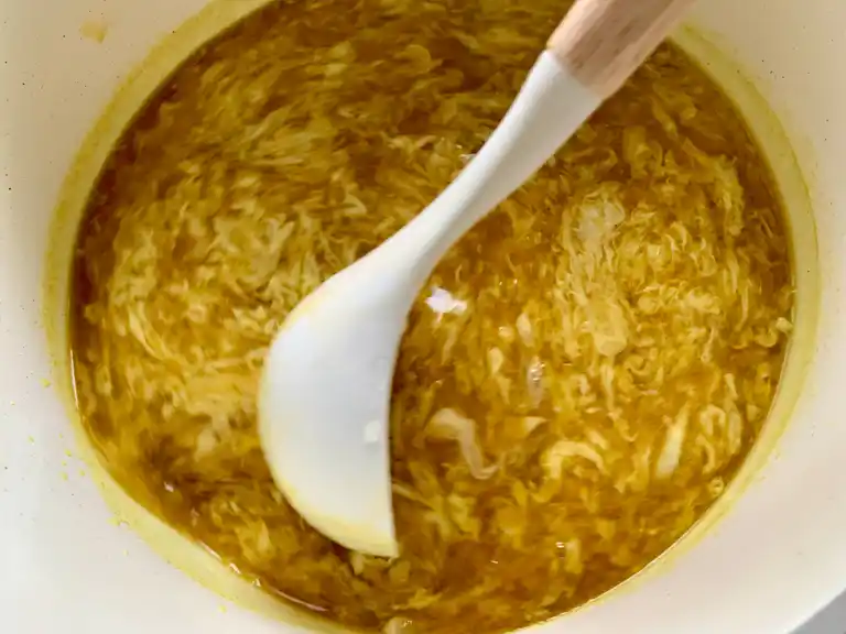 Eggs swirled into broth to form silky ribbons in egg drop soup.
