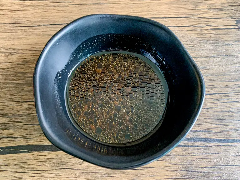 Soy-sesame salad dressing in a small black bowl.