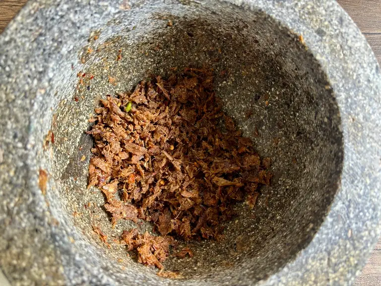 Finished jeow paa Lao dipping sauce with smoky grilled fish and chili paste texture in a mortar.