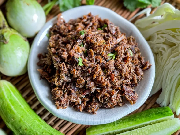 Traditional Lao jeow paa dipping sauce made with grilled dried fish, chilies, and padaek, served with fresh vegetables.