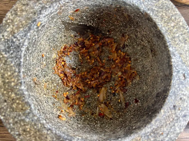 Chilies, garlic, and shallots pounded in a granite mortar.