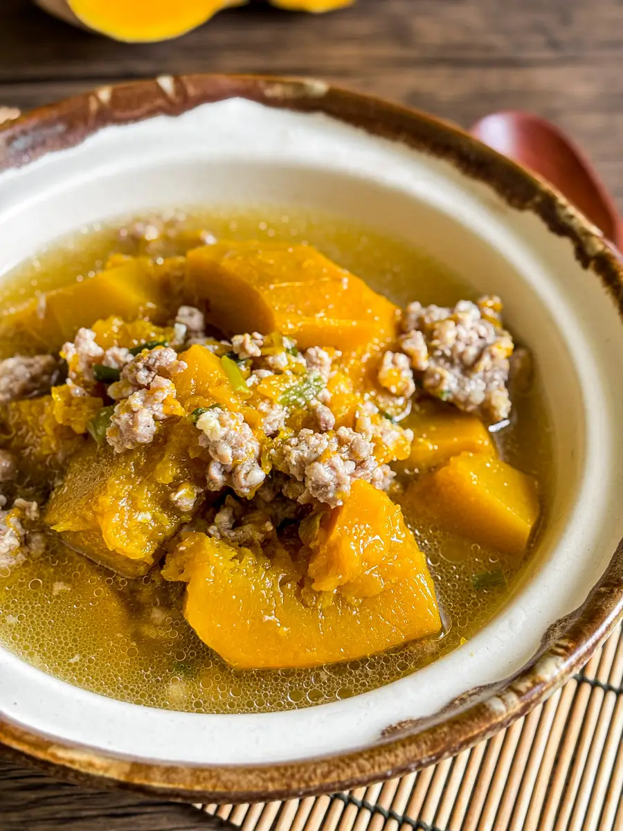 Canh bi do soup in ceramic bowl close-up – Vietnamese pumpkin soup with ground pork, served in clear broth with large chunks of pumpkin.