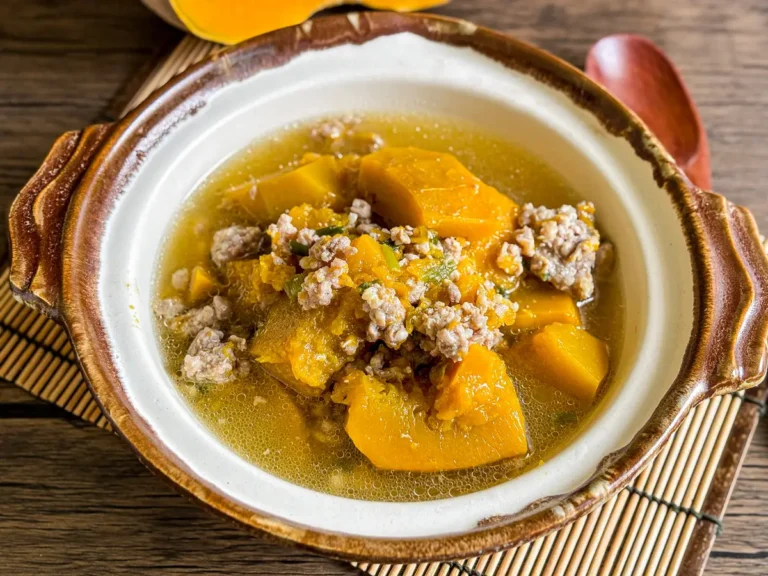 Vietnamese pumpkin soup (canh bi do) – golden pumpkin pieces and minced pork in a light, clear broth in rustic clay bowl.