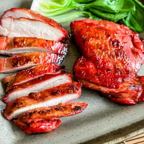Juicy grilled char siu chicken thighs sliced and served with bok choy.