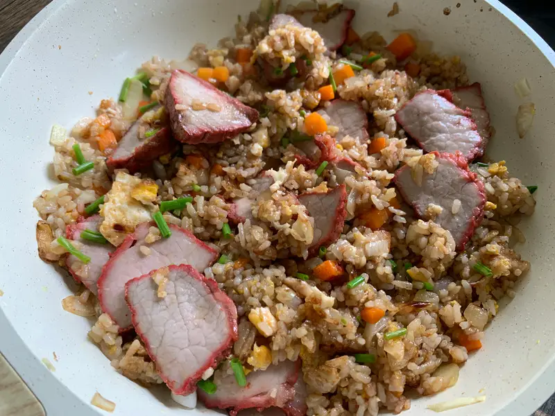 Finished char siu fried rice with pork slices and garnished with scallions.