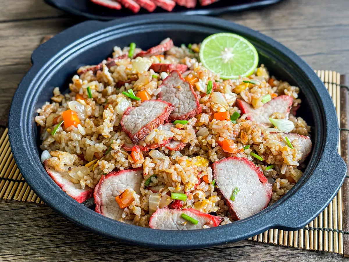 Char siu fried rice with red pork slices, diced carrots, and chopped scallions.