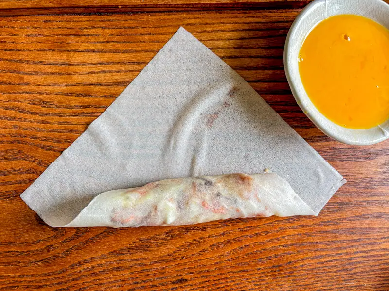 Folding the spring roll wrapper over the filling during rolling.