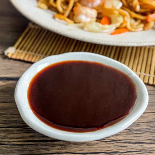 Homemade yakisoba sauce in a white dipping bowl on a wooden table.