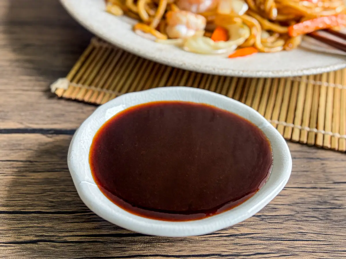 Homemade yakisoba sauce in a white dipping bowl on a wooden table.