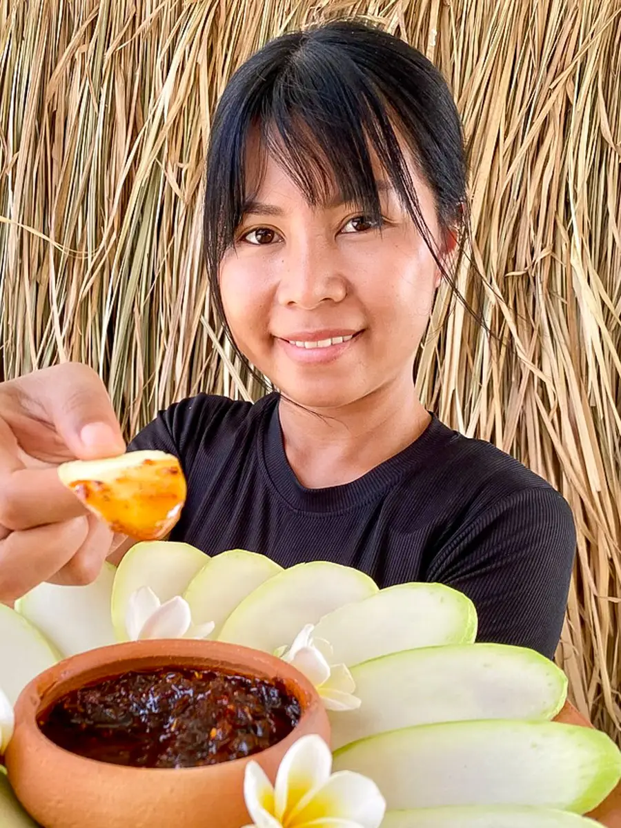 Praew holding a plate of sliced green mango with Thai chili dip.